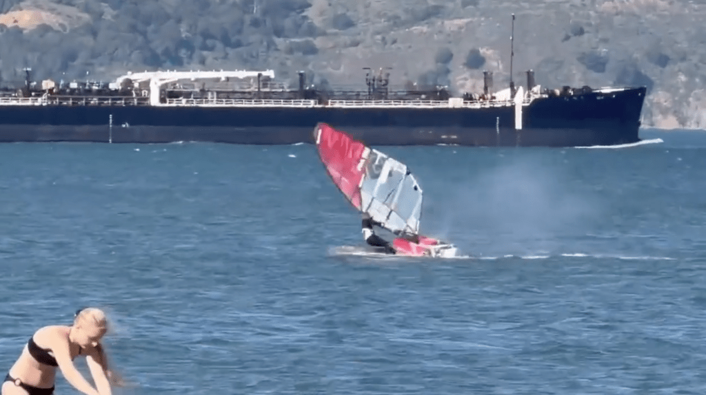 Windsurfer Eric Kramers colliding with a surfacing gray whale, sending him tumbling into the water.