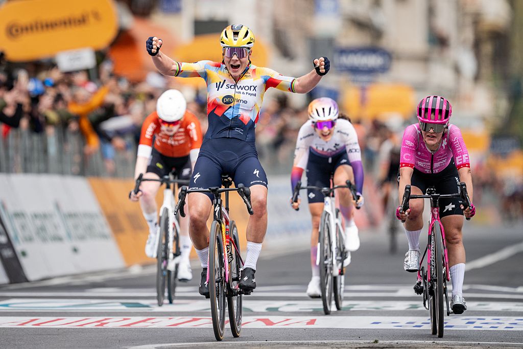 Kopecky raises her arms at the line with three other riders behind