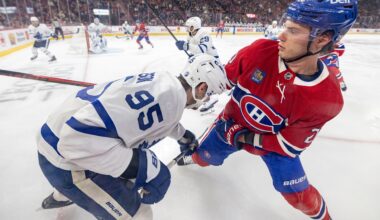 Two hockey players grapple along the boards in a close-up view.