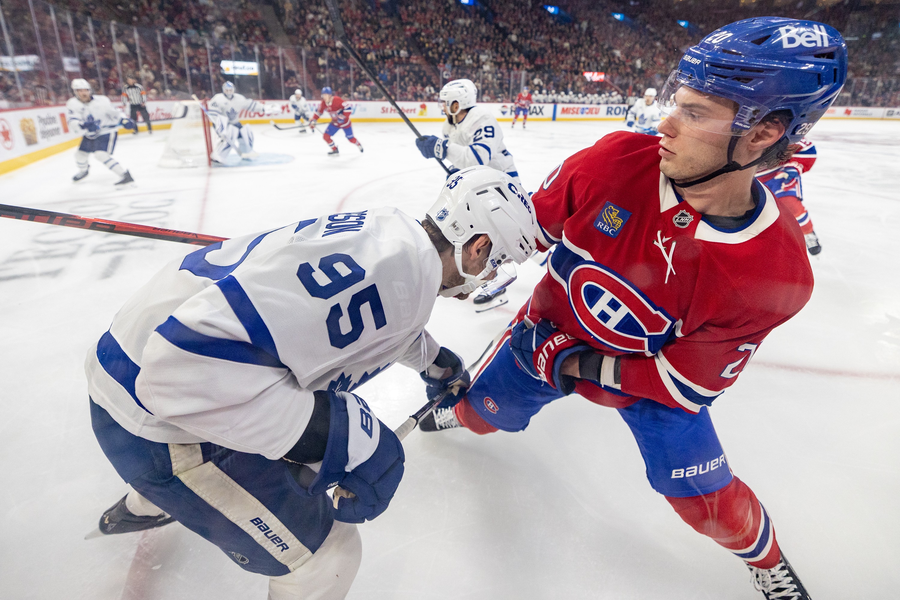 Two hockey players grapple along the boards in a close-up view.