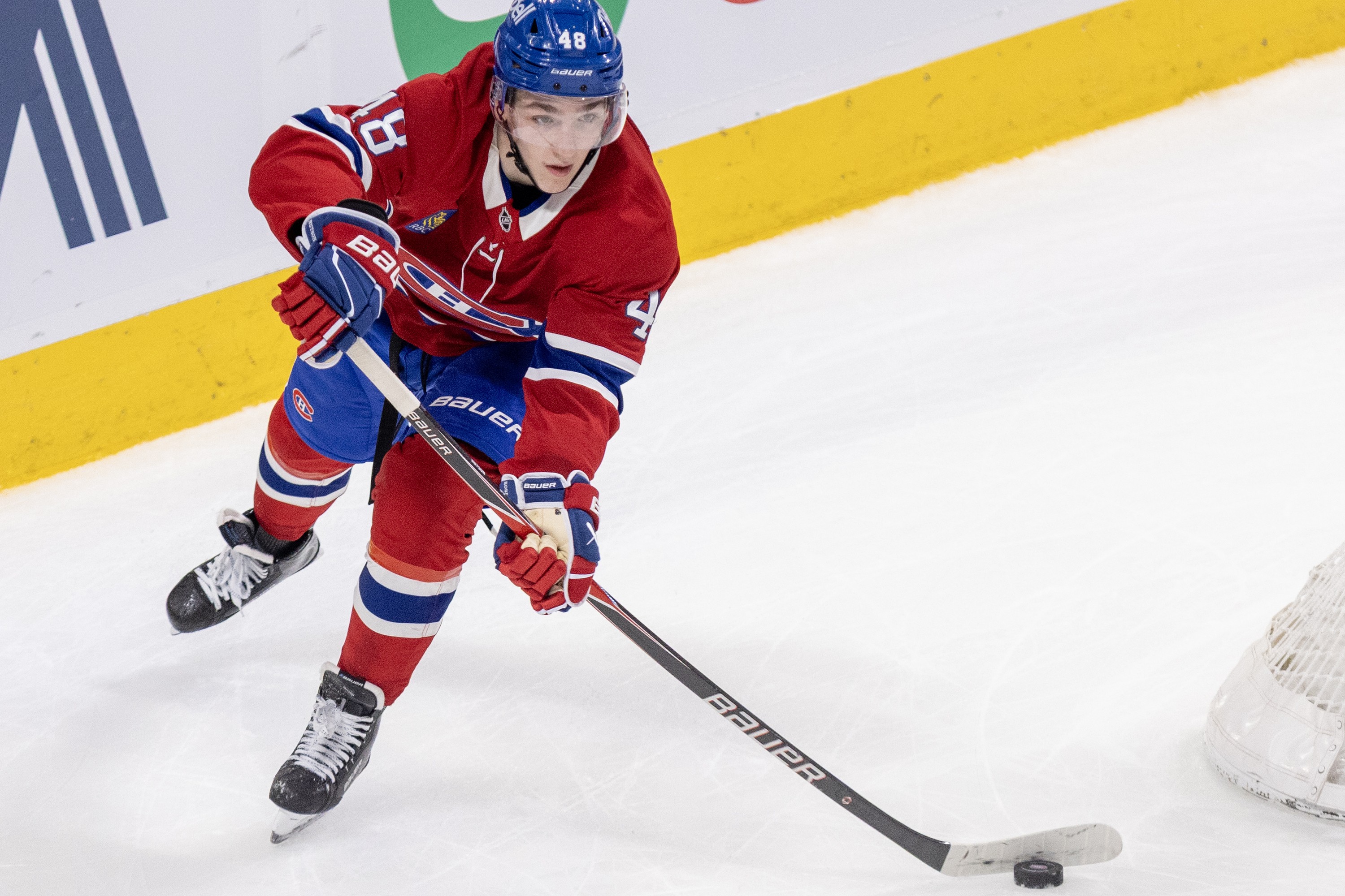 Hockey player's stick bends as he passes the puck up the ice.