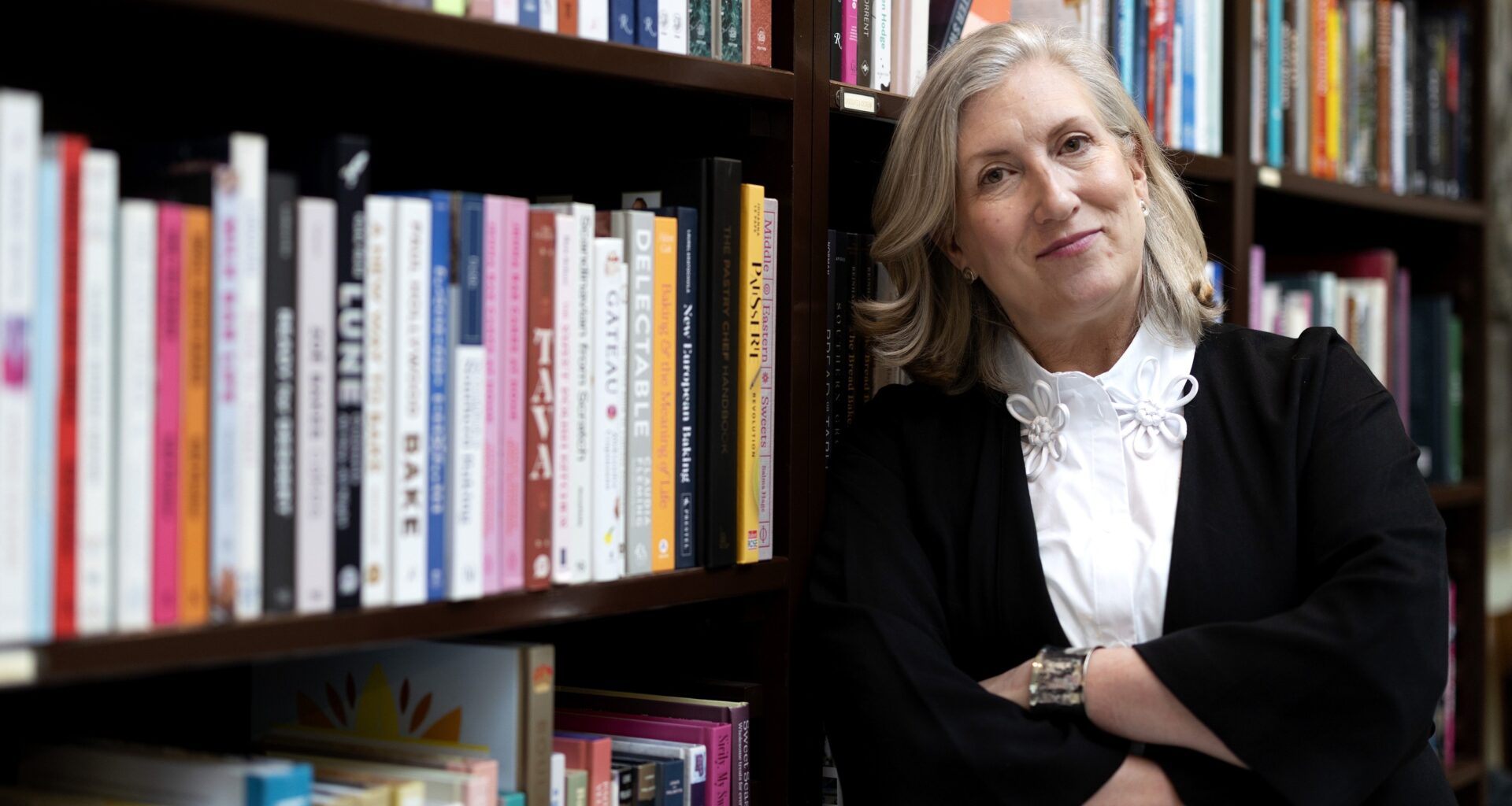 Food writer Lesley Chesterman leans against a bookcase in a bookstore.