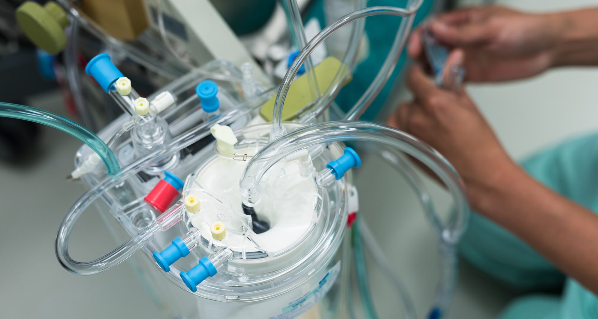 The hands of a perfusionist preparing heart-lung bypass equipment.