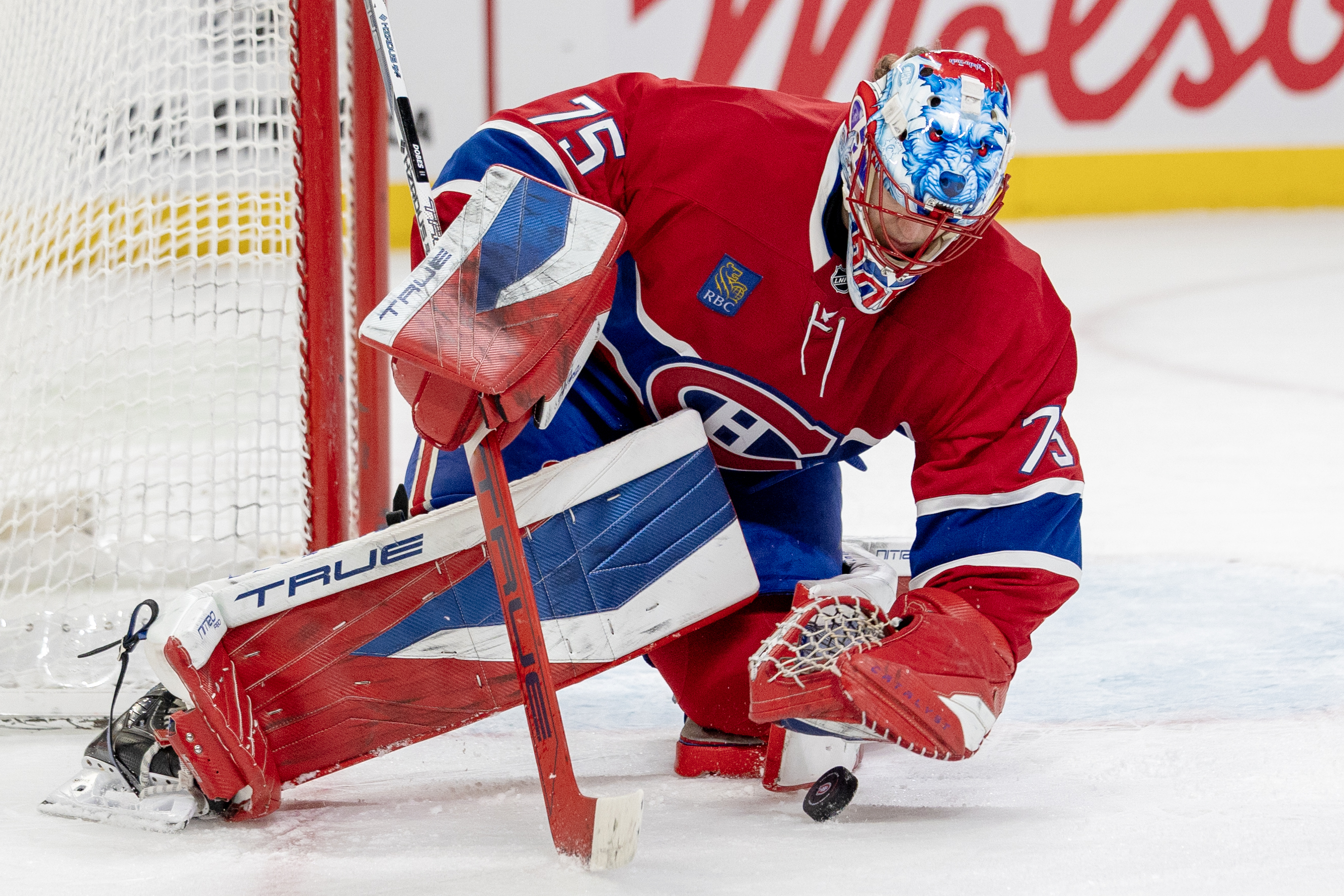 Hockey goalie kneels down to make a stop. 