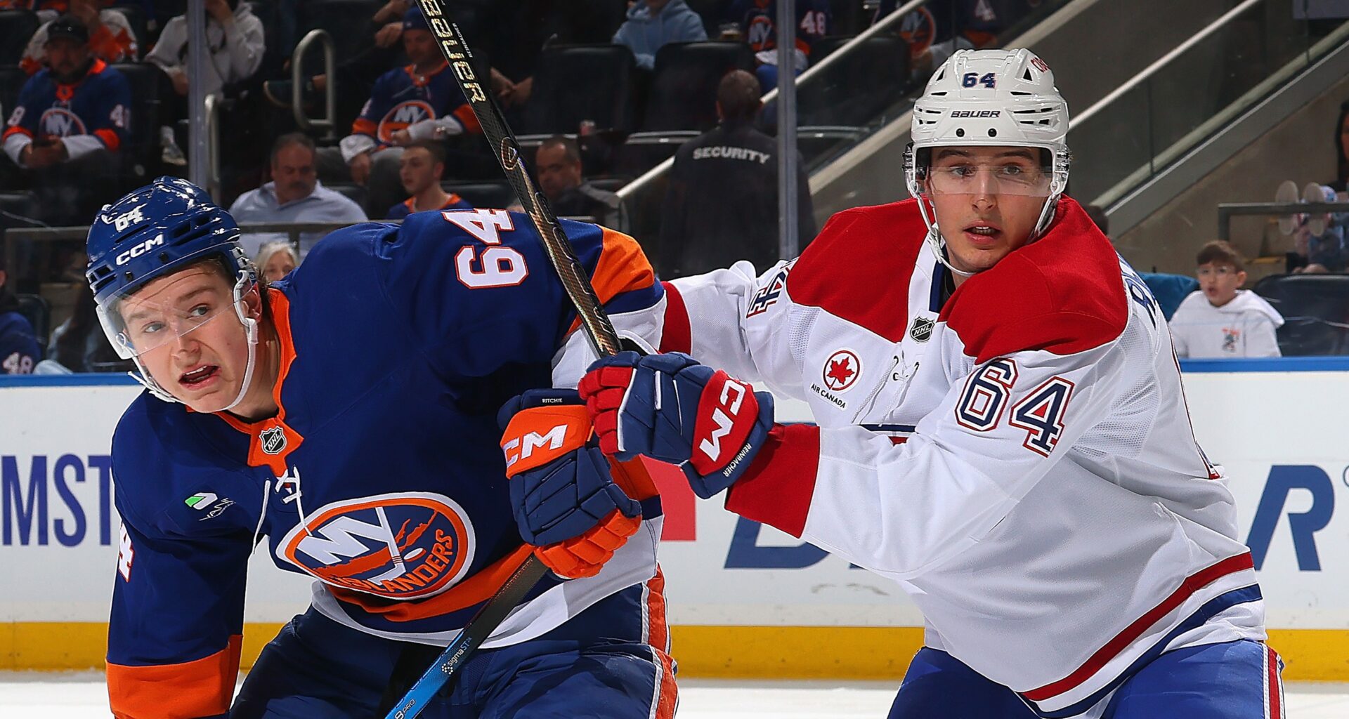 David Reinbacher of the Montreal Canadiens checks Calum Ritchie of the New York Islanders.