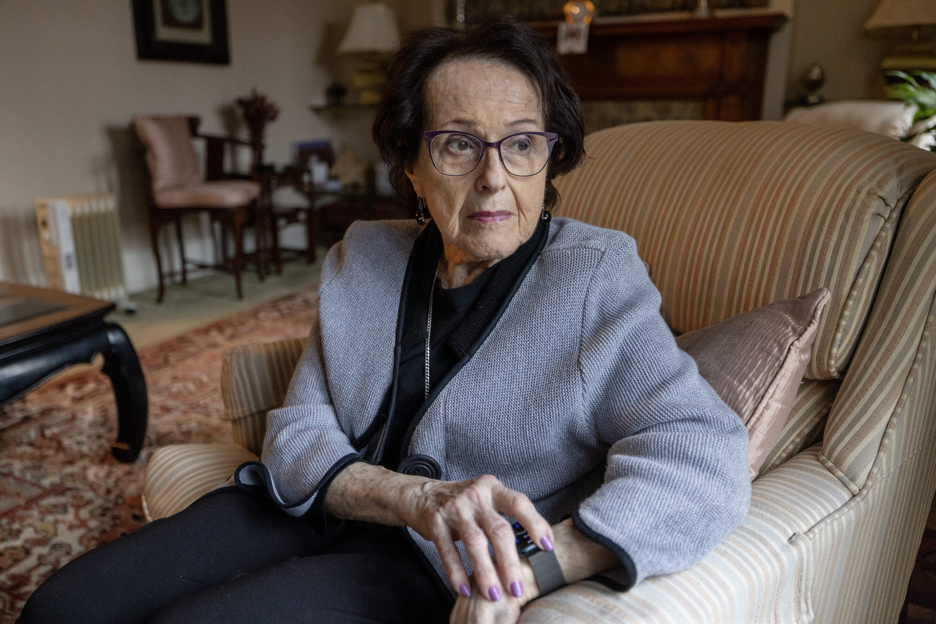 A woman stares to the side of the camera while sitting in her living room.