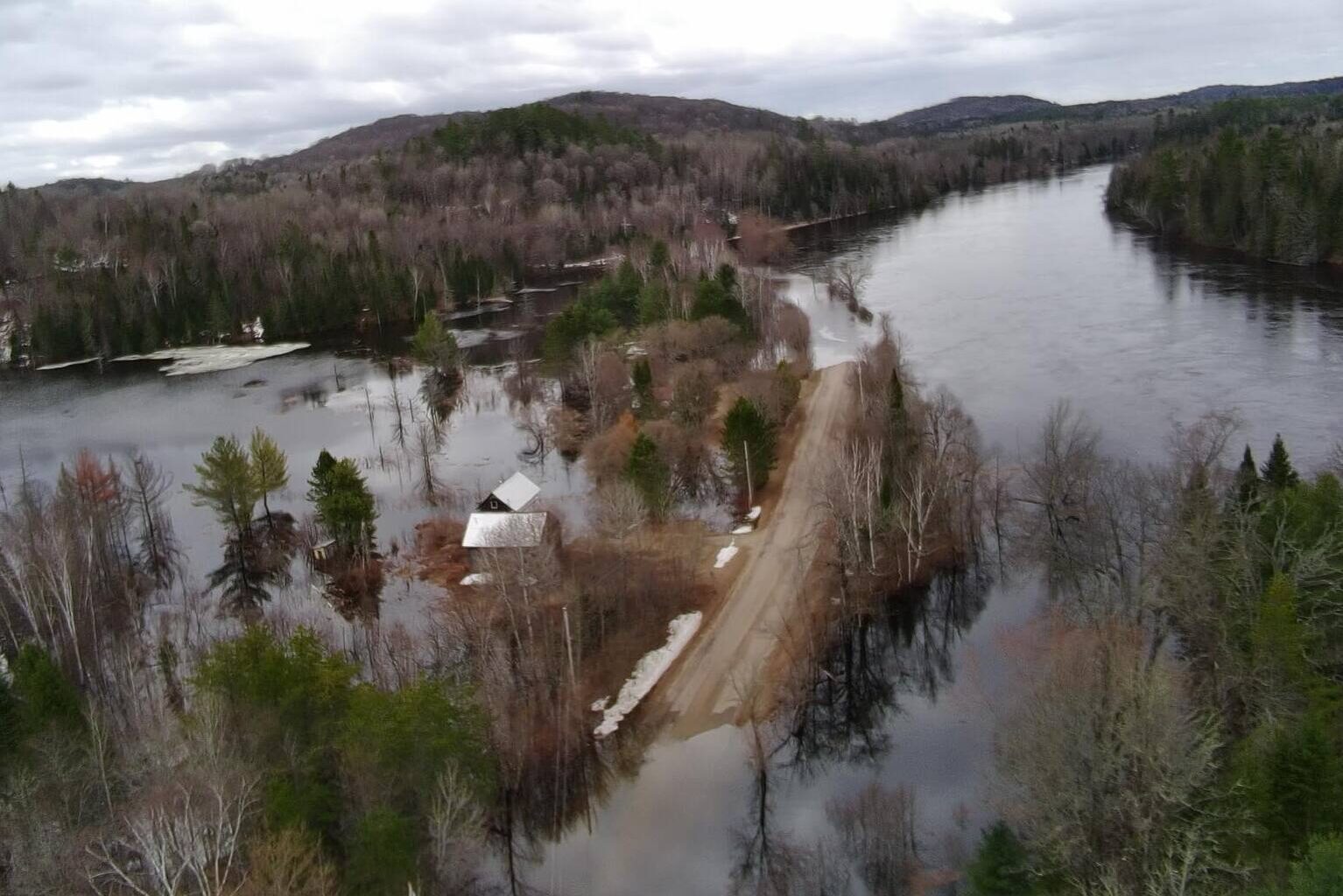 Aerial image shows a flooded road with rising waters on either side of it.