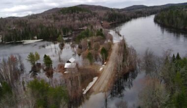 Aerial image shows a flooded road with rising waters on either side of it.