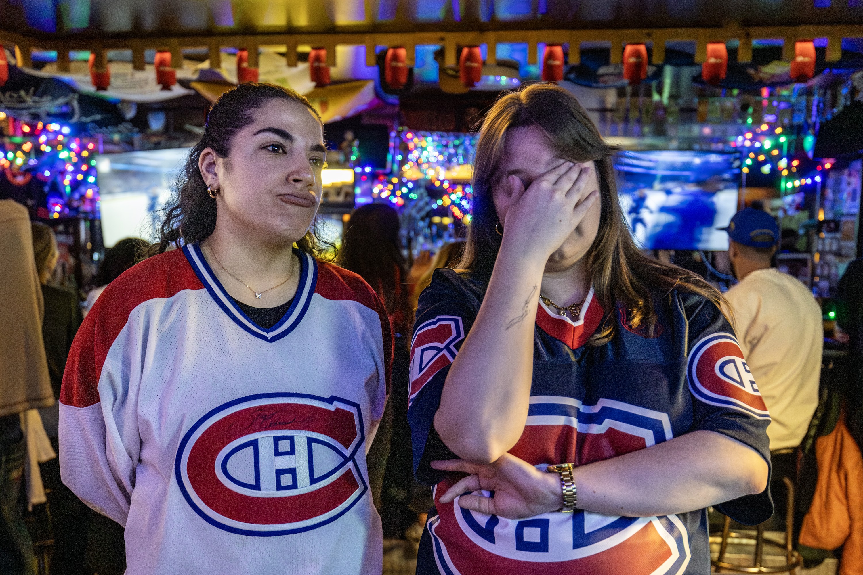 Montreal Canadiens fans Rachel Awada, left, and Brianna Klint react as the Tampa Bay Lightning defeat the Habs in overtime, while watching the playoff game at Double's in Montreal, Tuesday April 21, 2026. 