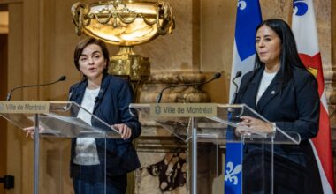 Two women stand at podiums addressing the media