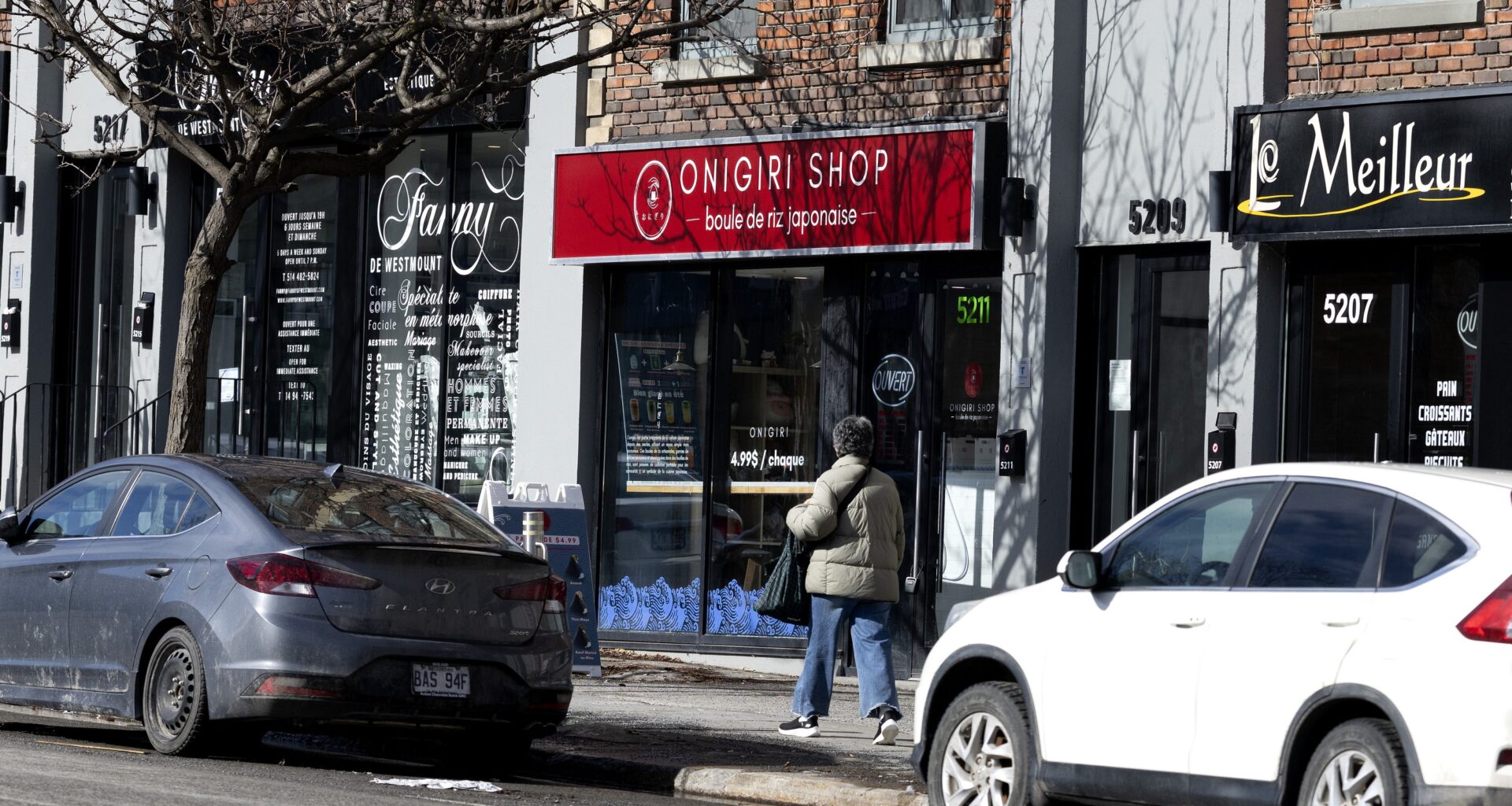 Two cars parked on a street in front of businesses in wintertime.