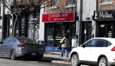 Two cars parked on a street in front of businesses in wintertime.