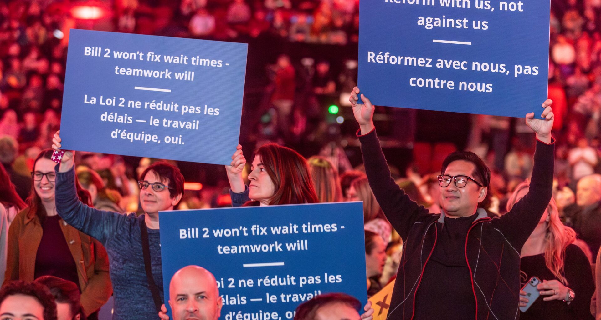 Quebec doctors hold up signs against Bill 2 at a packed Bell Centre last November.