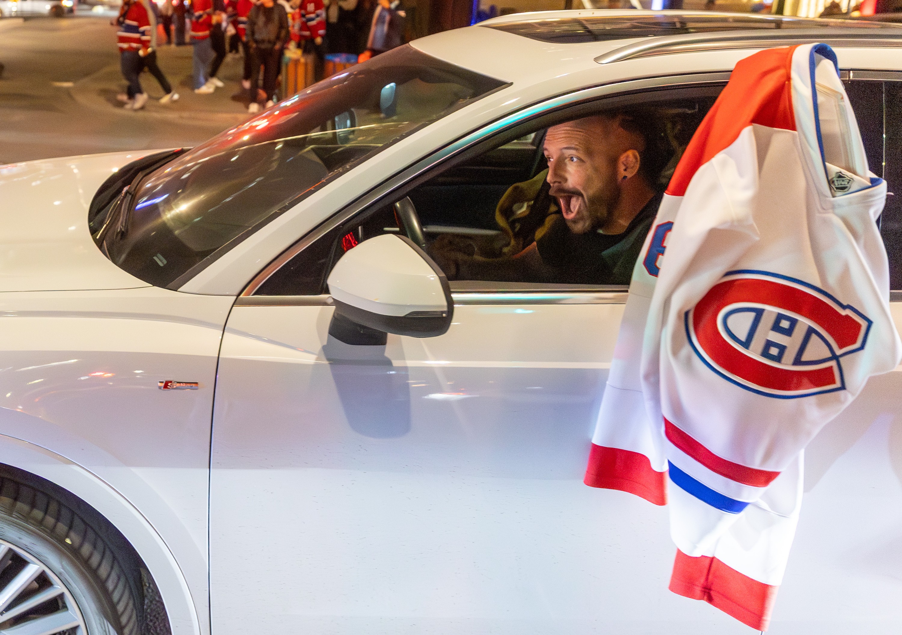 A jubilant Habs fan waves a white Canadiens jersey outside his car while driving away from the game Friday night in downtown Montreal.
