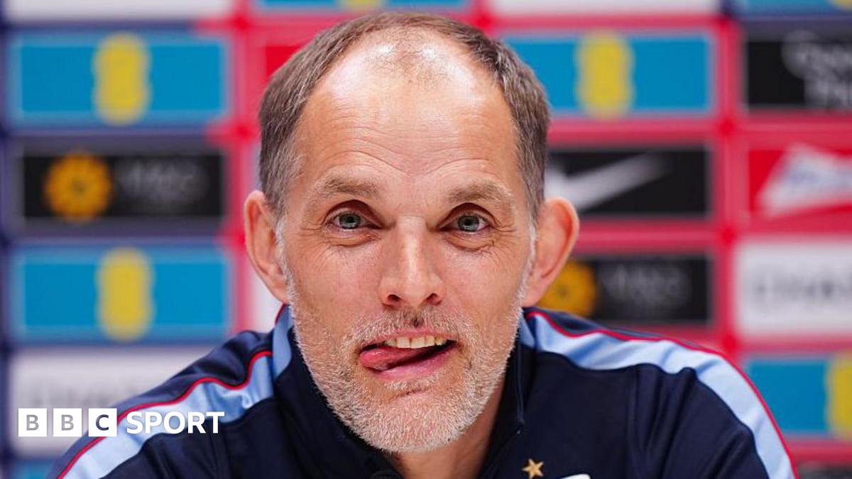Head and shoulders view of England head coach Thomas Tuchel at a news conference, with his tongue poking out of his mouth