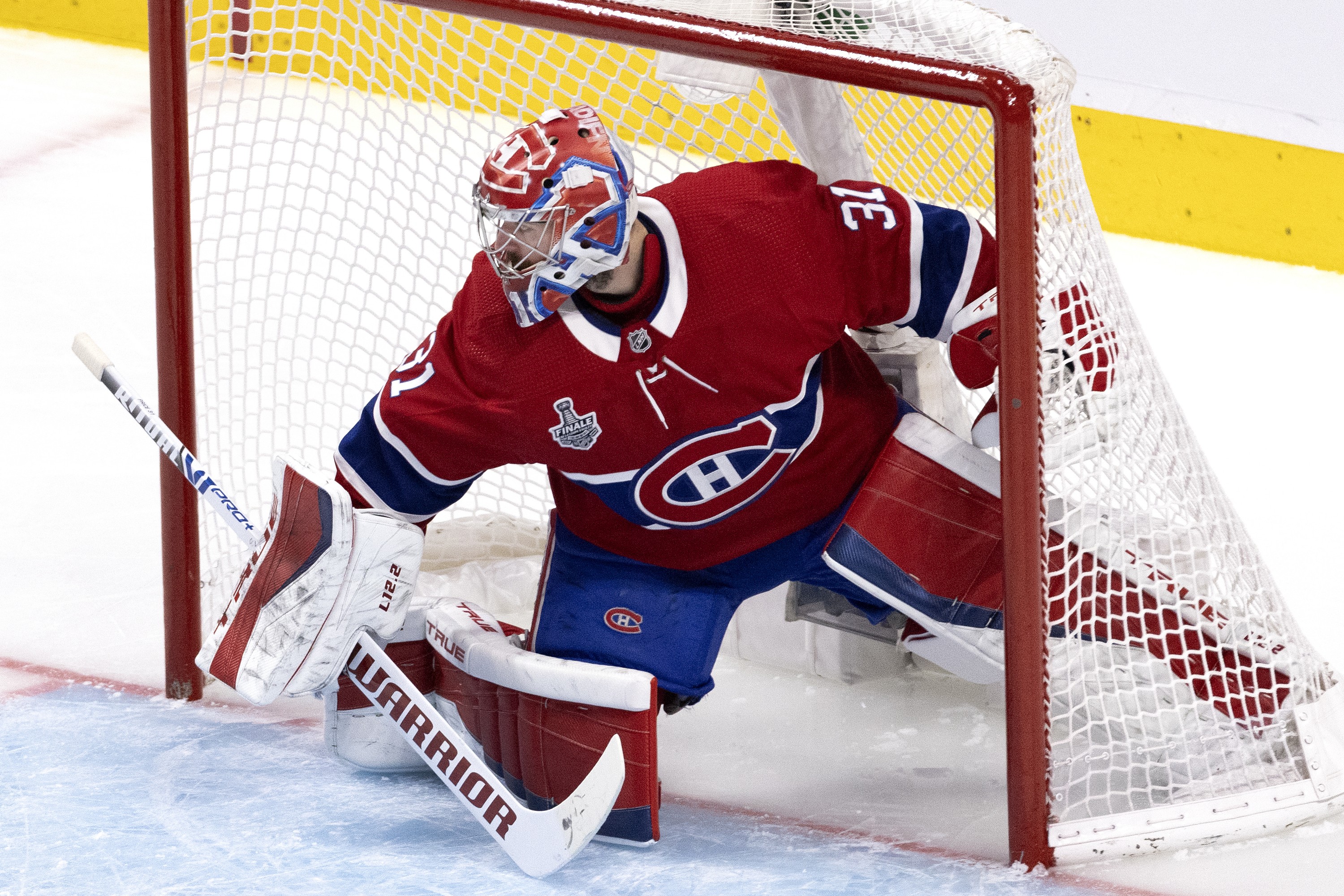 Hockey goalie is deep in his net.