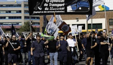 Workers hold up a large banner with the STM maintenance union logo on it.