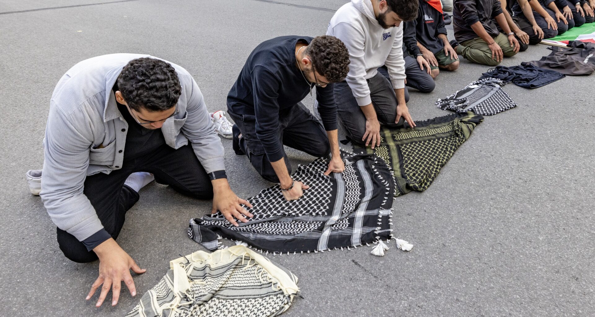 Several Muslim men pray on a city street.