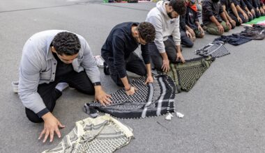 Several Muslim men pray on a city street.