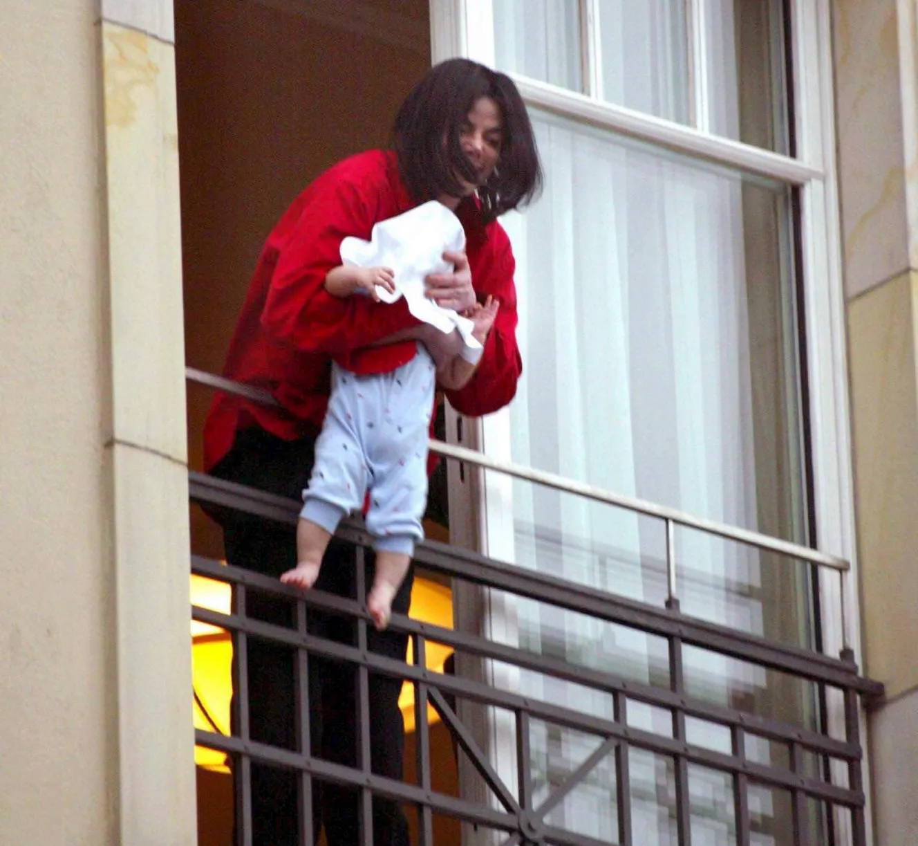 Michael Jackson dangles his baby son, Prince Michael II, over a balcony.