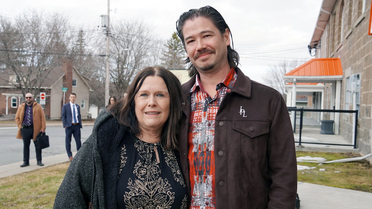 A man and a woman smiling outside.
