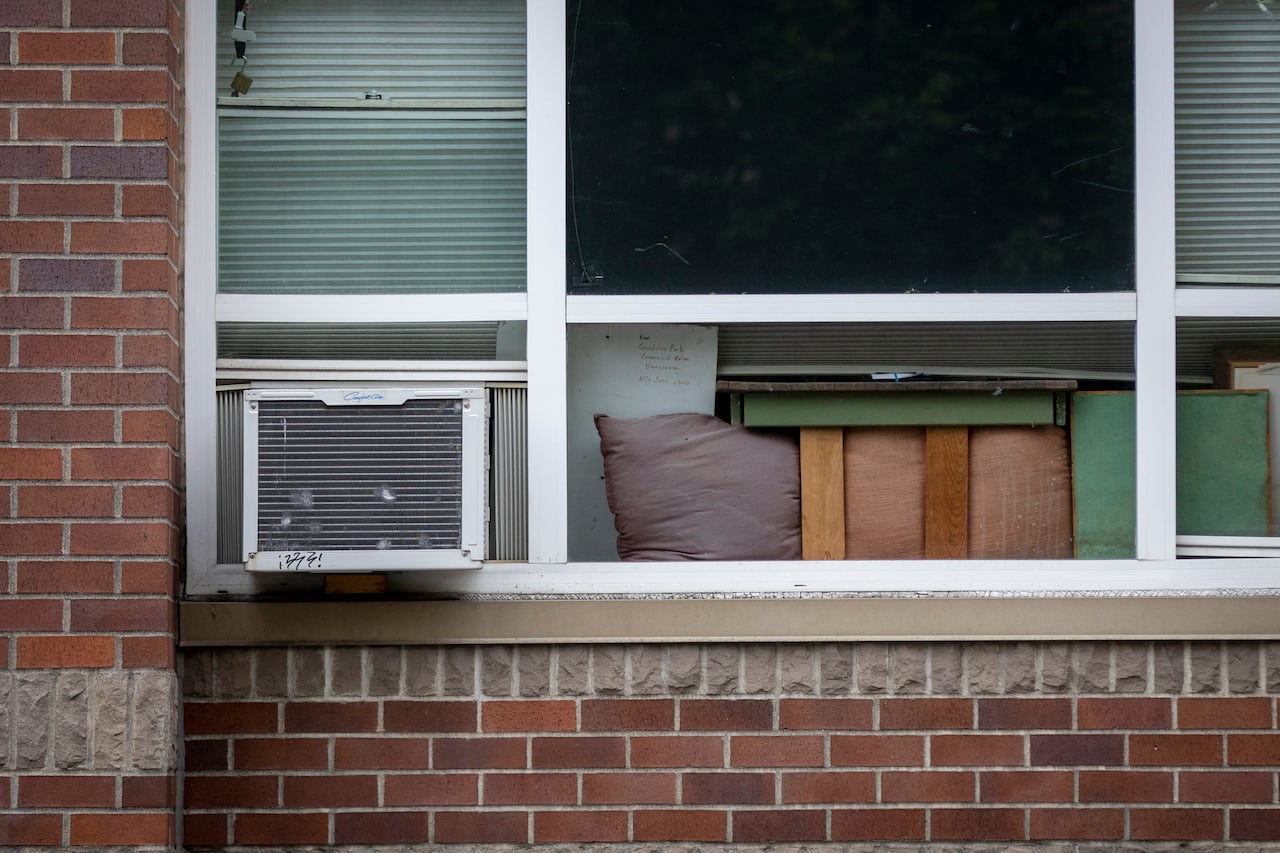 A photo of an apartment window with an air conditioning unit in it.