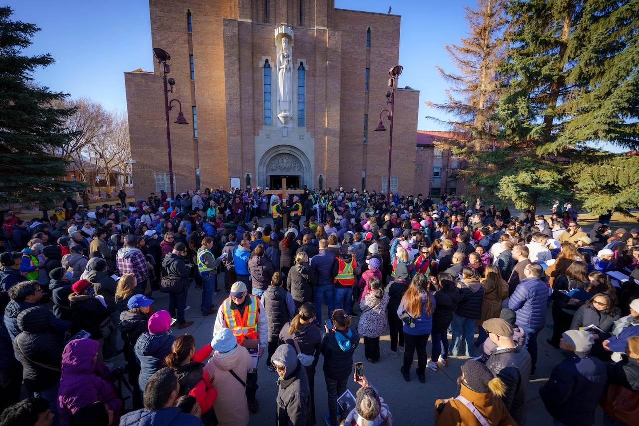 A crowd of people gathered outside a cathedral on a sunny day.