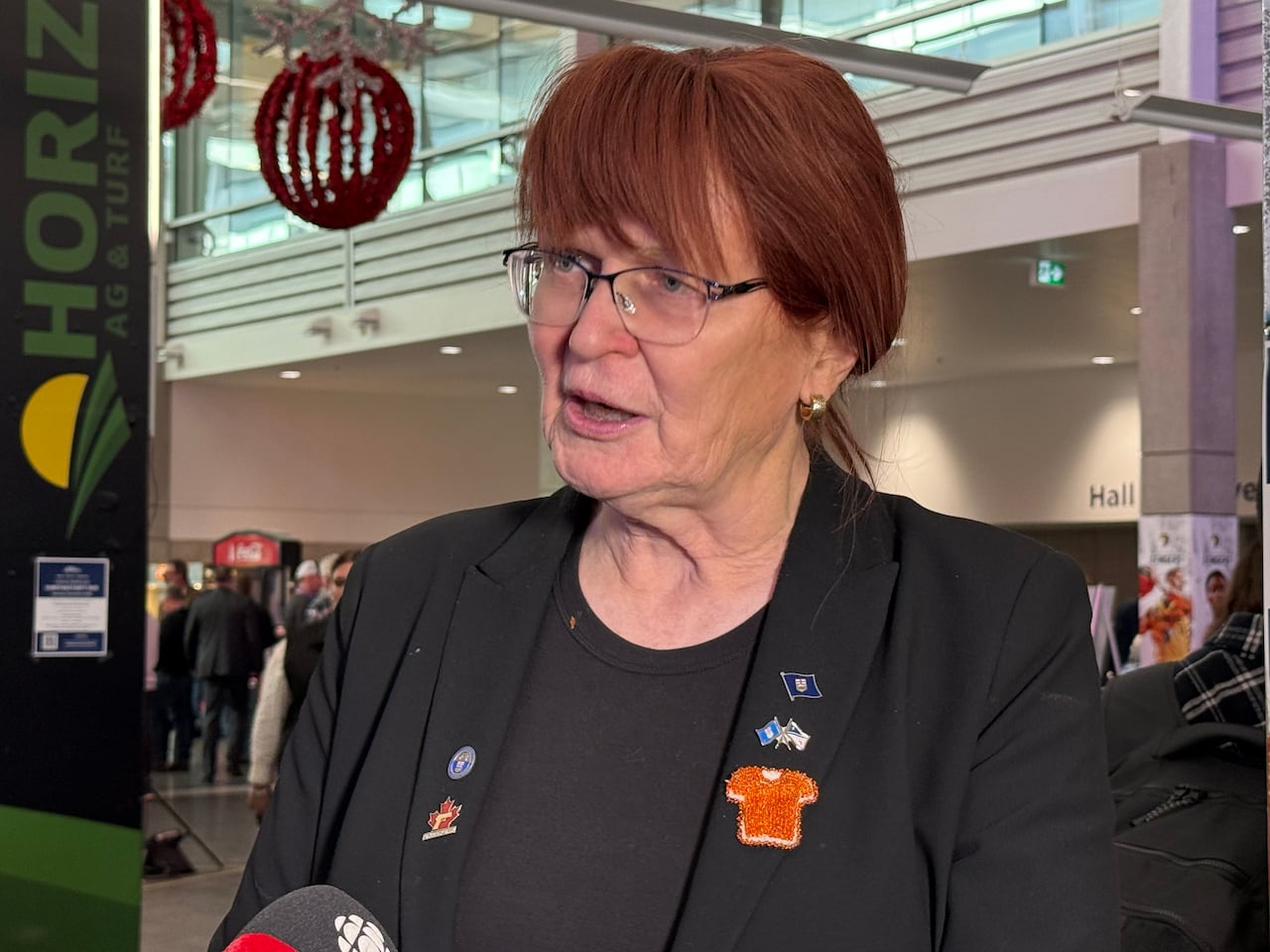 A woman wearing all black speaks to reporters.