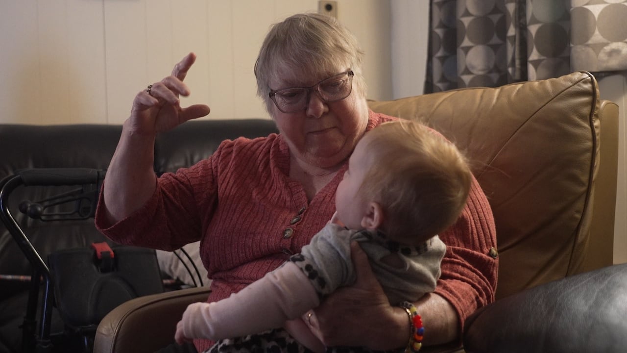A woman in a living room plays with a young child.