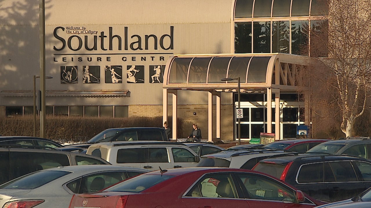 A metal-clad building with a full parking lot in front of it.