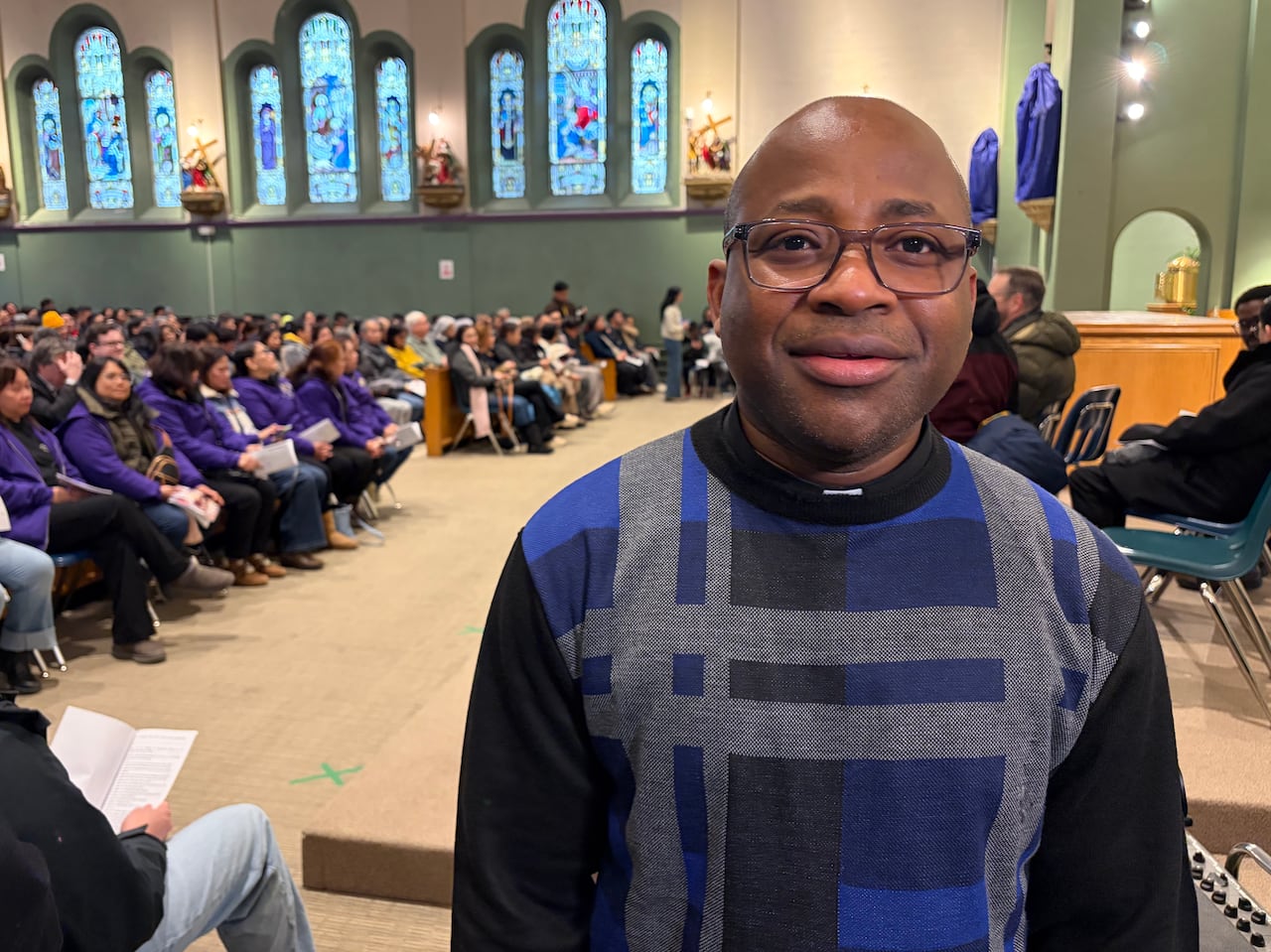 A man with glasses smiles.