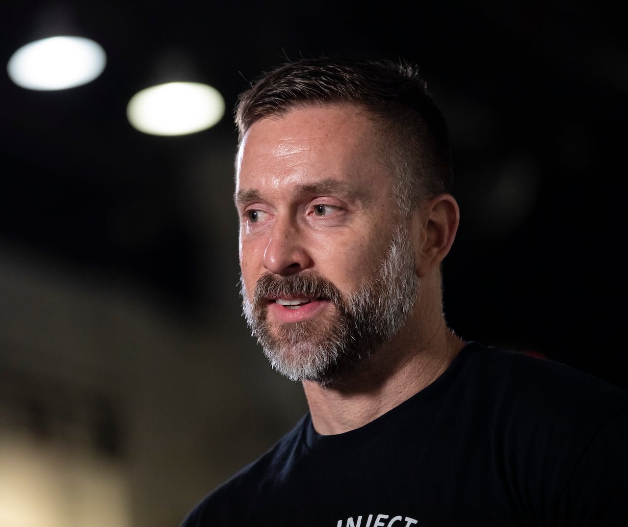 A white man with a salt-and-pepper beard is seen speaking.