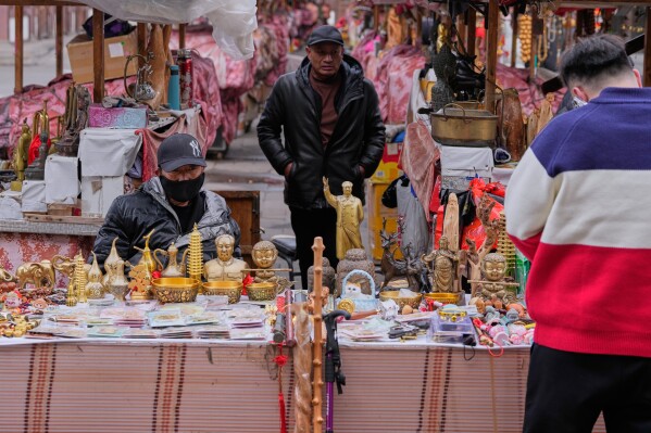 Vendors selling trinkets wait for tourists at Yungang Grottoes in Datong, China, Friday, March 13, 2026. (AP Photo/Ng Han Guan)