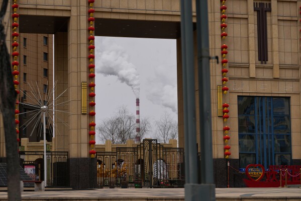 A chimney of a coal-fired power plant is visible near a residential complex in Datong, China, Saturday, March 14, 2026. (AP Photo/Ng Han Guan)