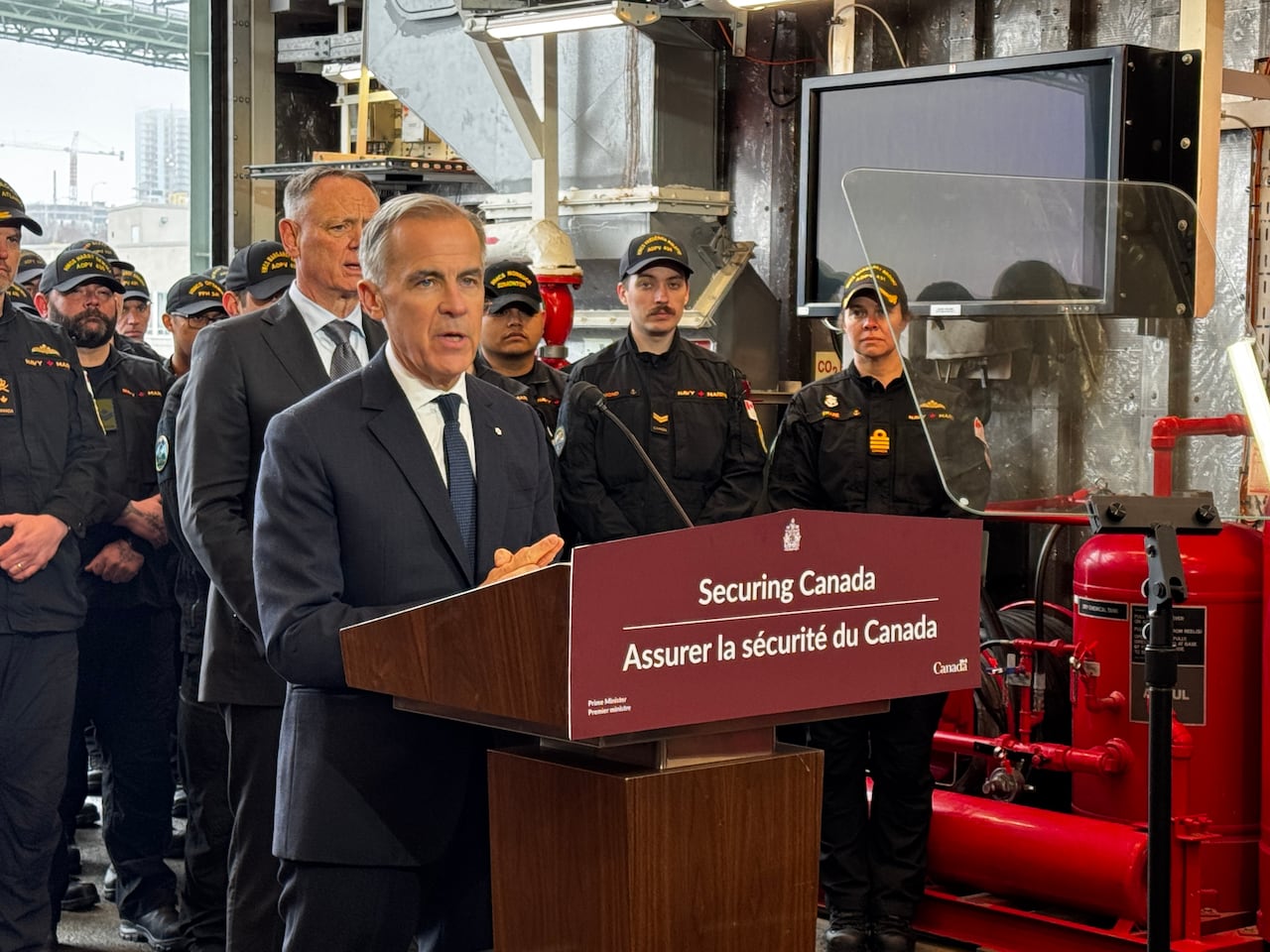 a man at a podium with sailors behind him