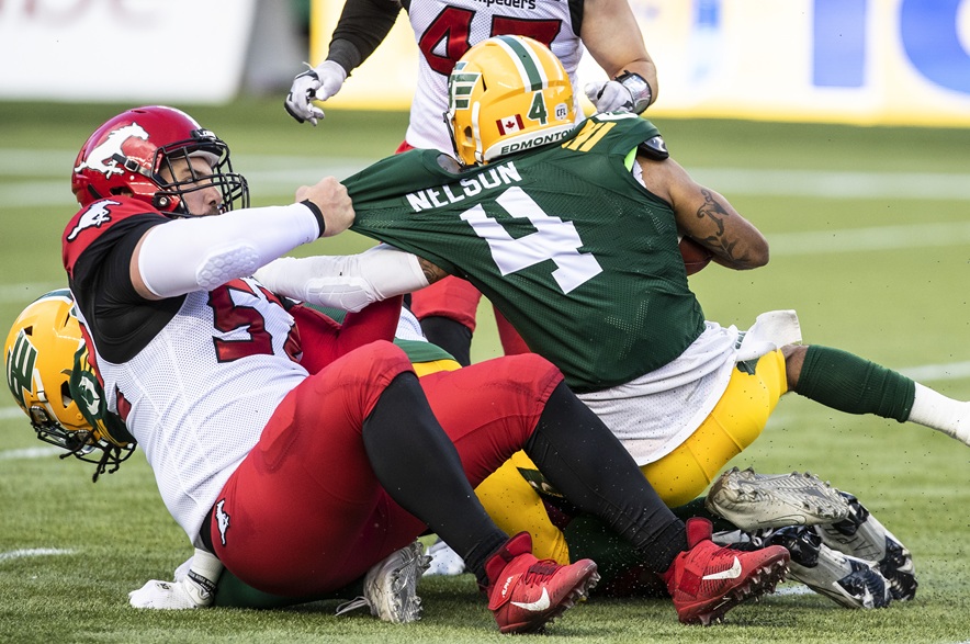Calgary Stampeders long snapper Aaron Crawford (52) tackles Edmonton Eskimos wide receiver Charles Nelson (4) during first half CFL action in Edmonton, Alta., on Thursday July 7, 2022.