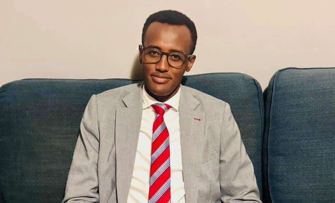 A man with glasses and a suit sitting on a couch