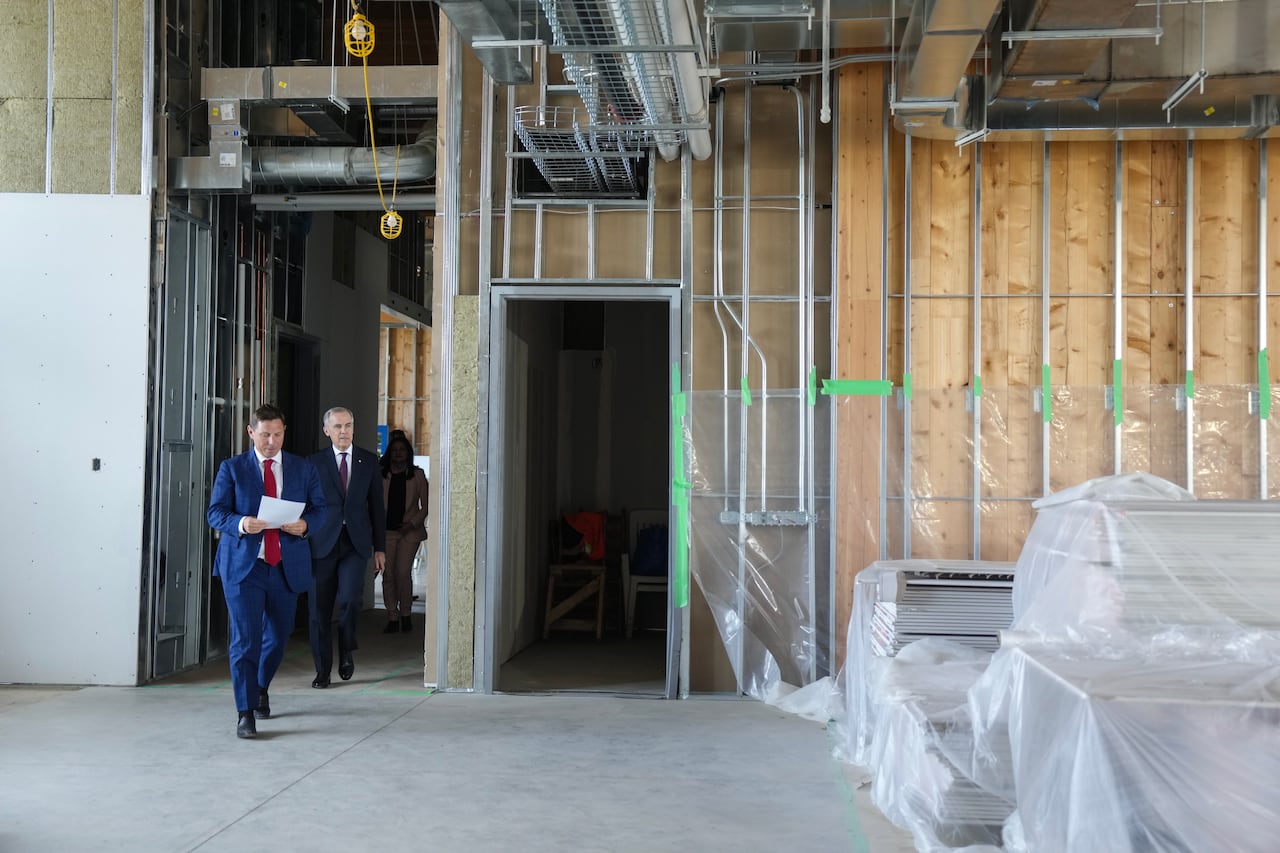 Two men in suits walking into a room under construction.