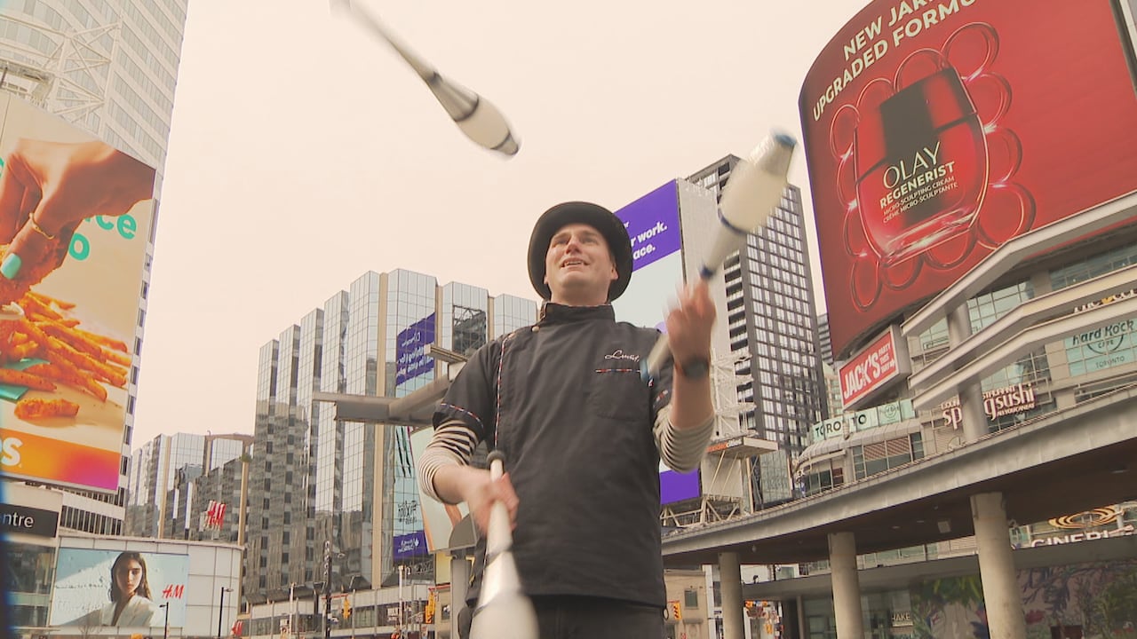 A man standing in Sankofa Square in Toronto juggling bowling pins