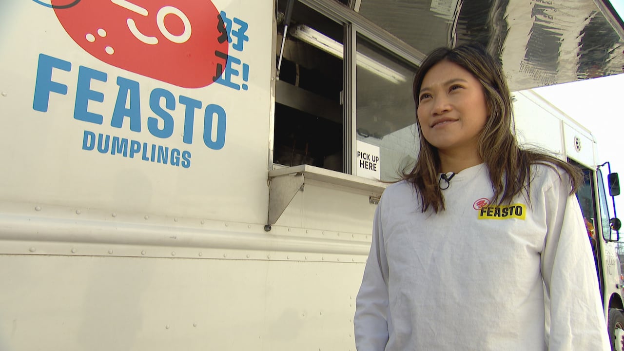 A woman standing in front of a food truck with an open window.