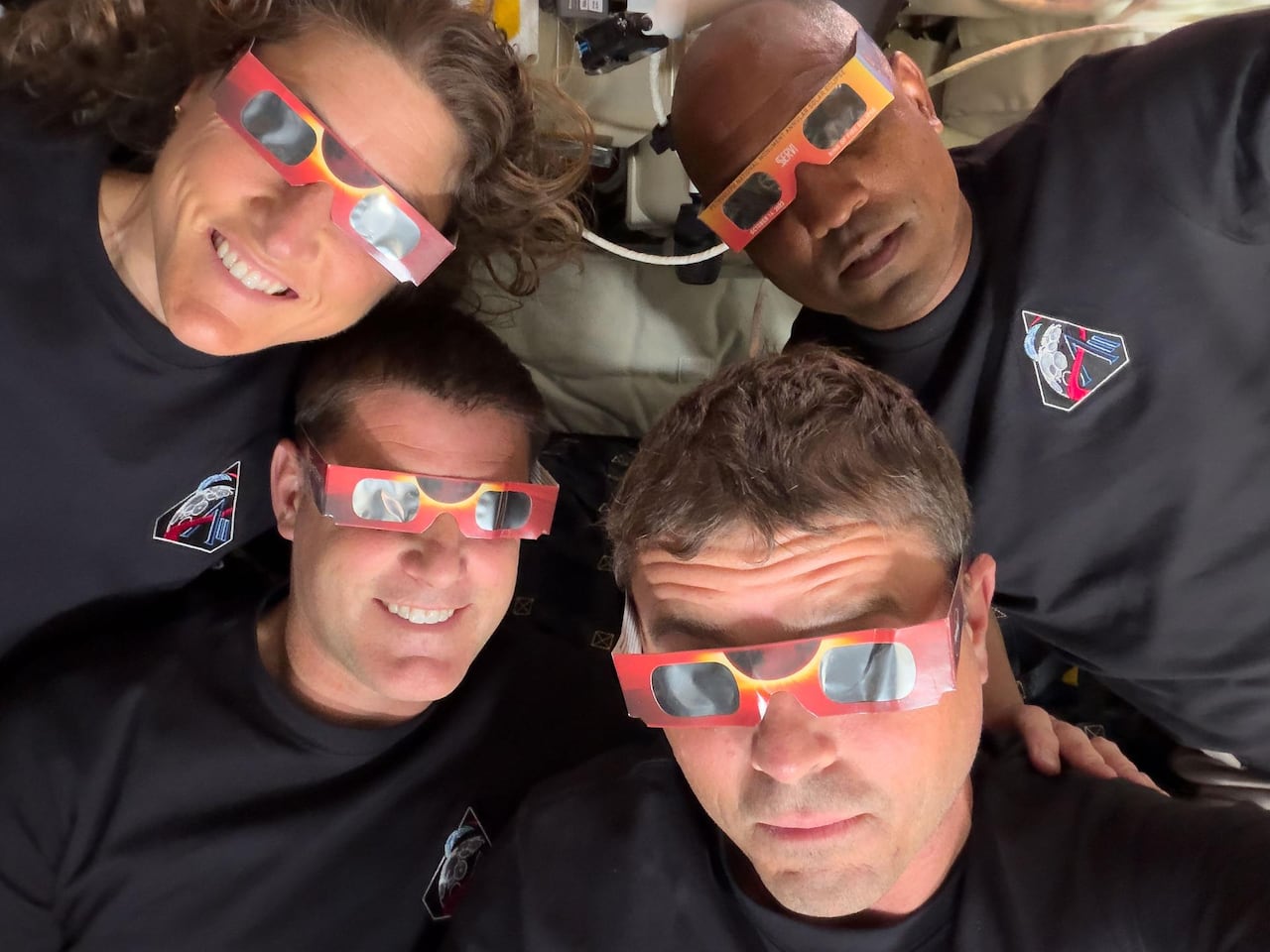 Four people take a selfie while wearing eclipse viewers.