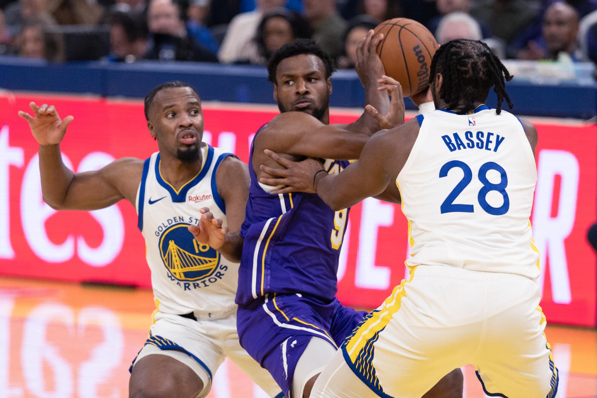 Lakers guard Bronny James looks to pass under pressure from Golden State's LJ Cryer, left, and Charles Bassey.
