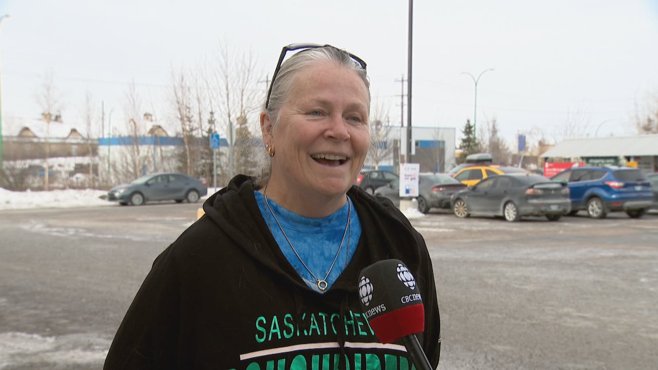 A woman in a black hoodie smiling outdoors.