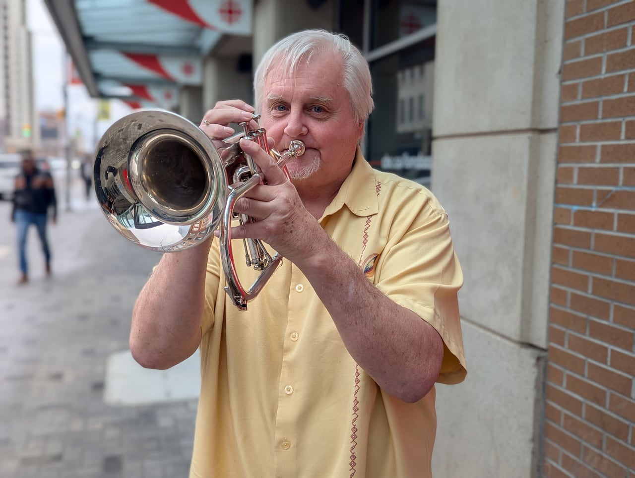 MacFadden plays a few notes on a horn on Dundas Street. 