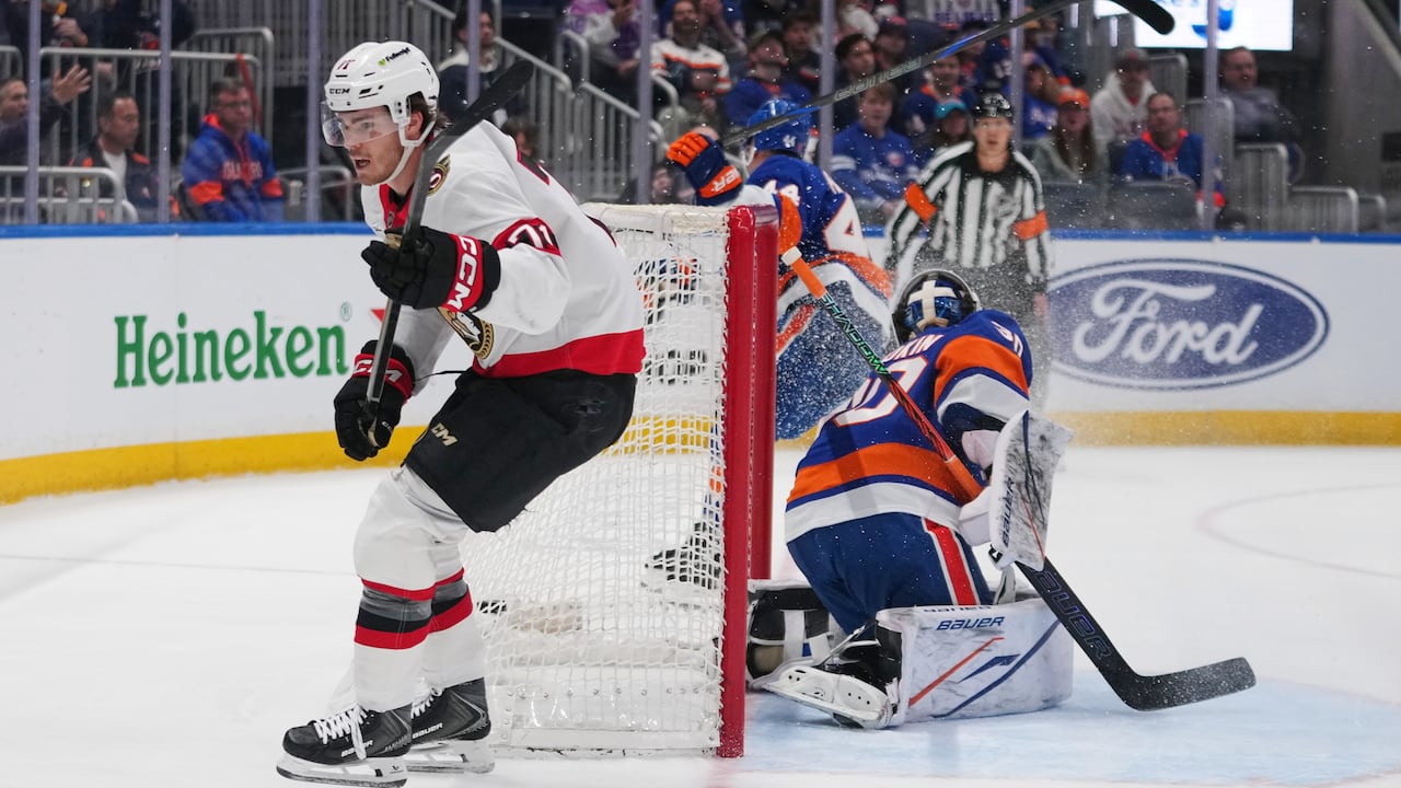 A hockey player skates past the opposing team's goaltender after scoring a goal.