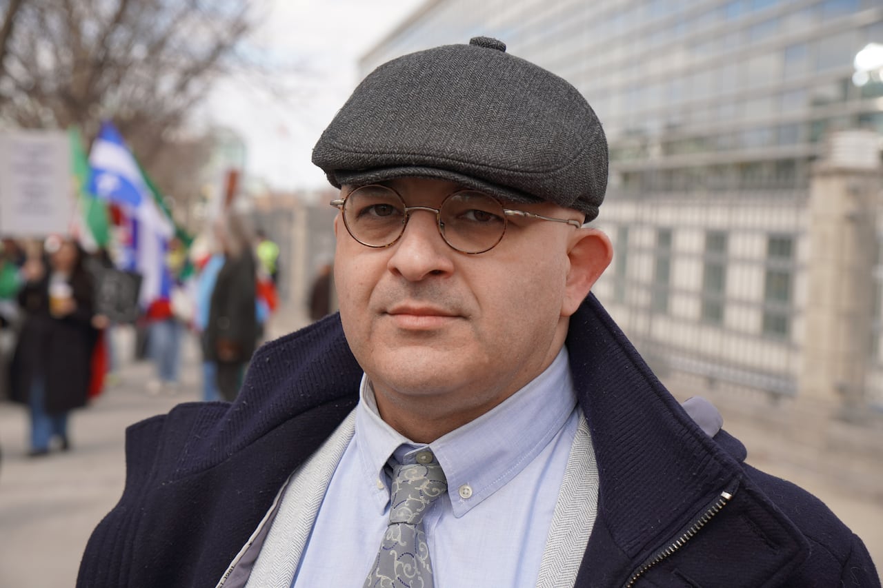 A portrait of a mean wearing glasses and a hat.