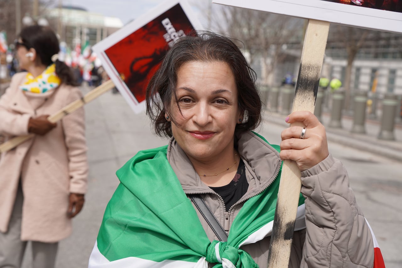 A portrait of a woman wearing an Iranian flag around her shoulders.