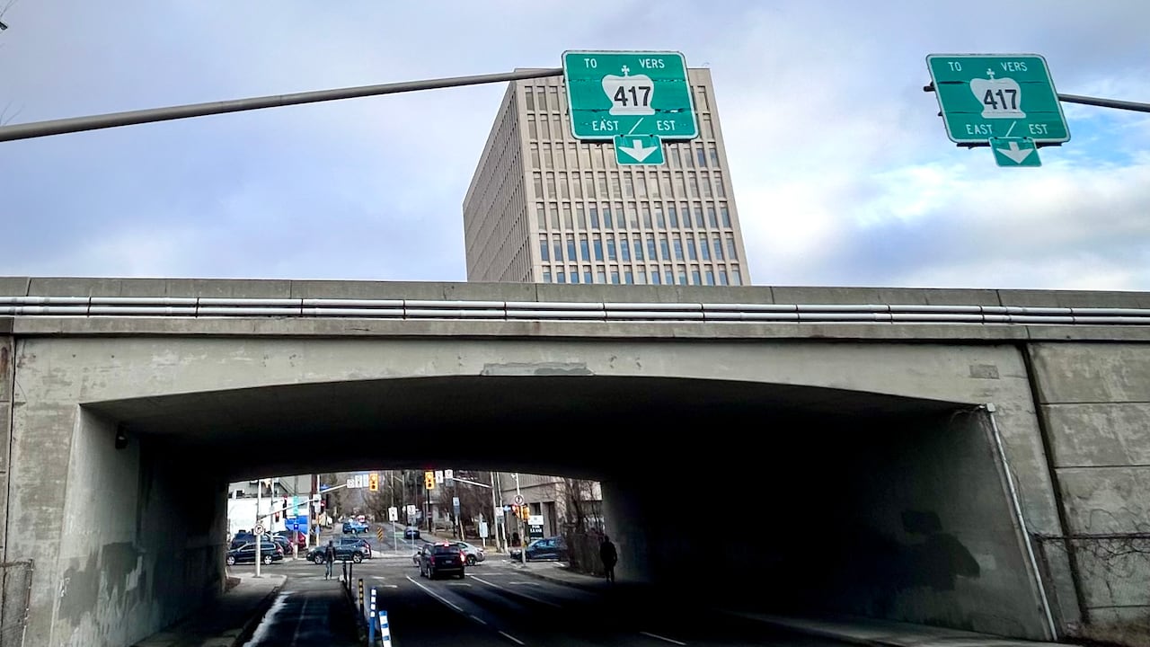 An overpass over a city street with highway signs above it.