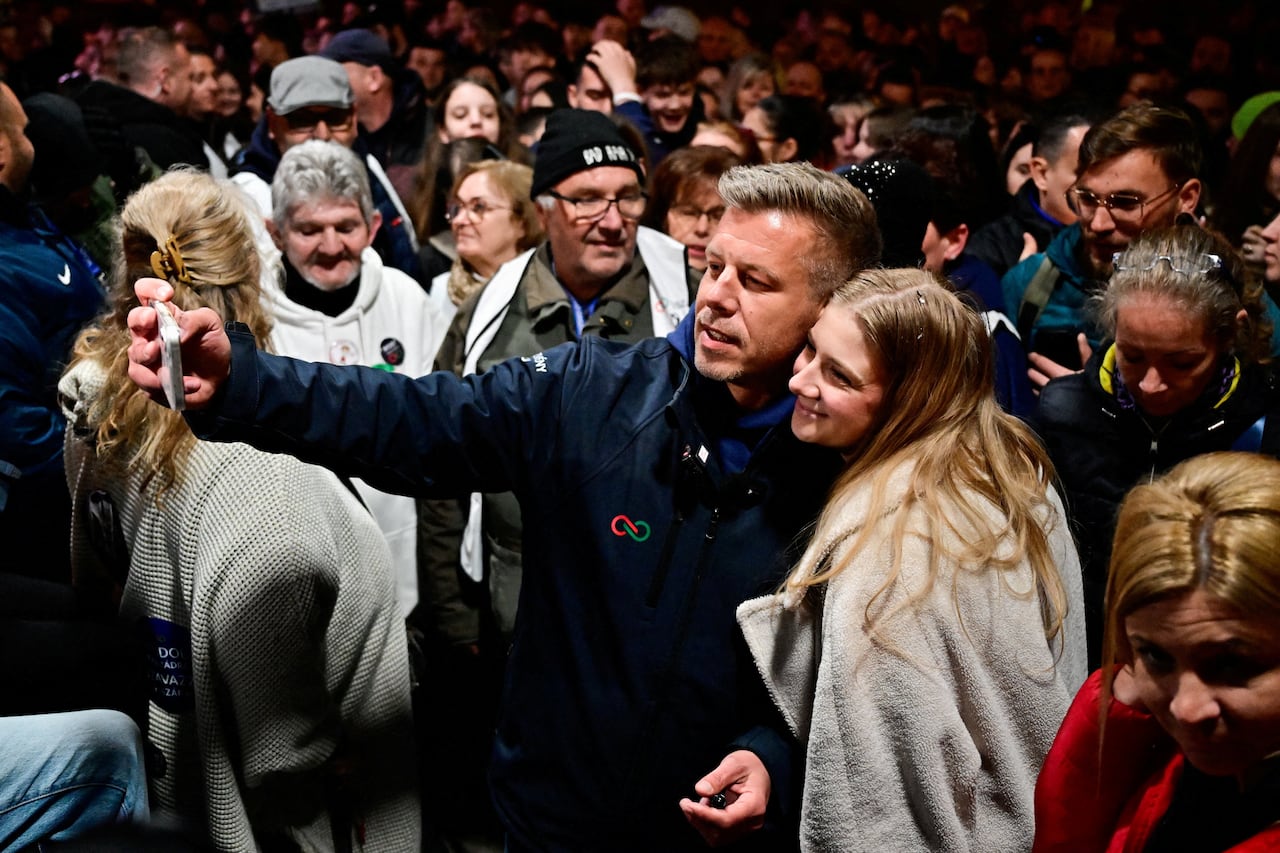 Two people take a selfie amid a crowd.