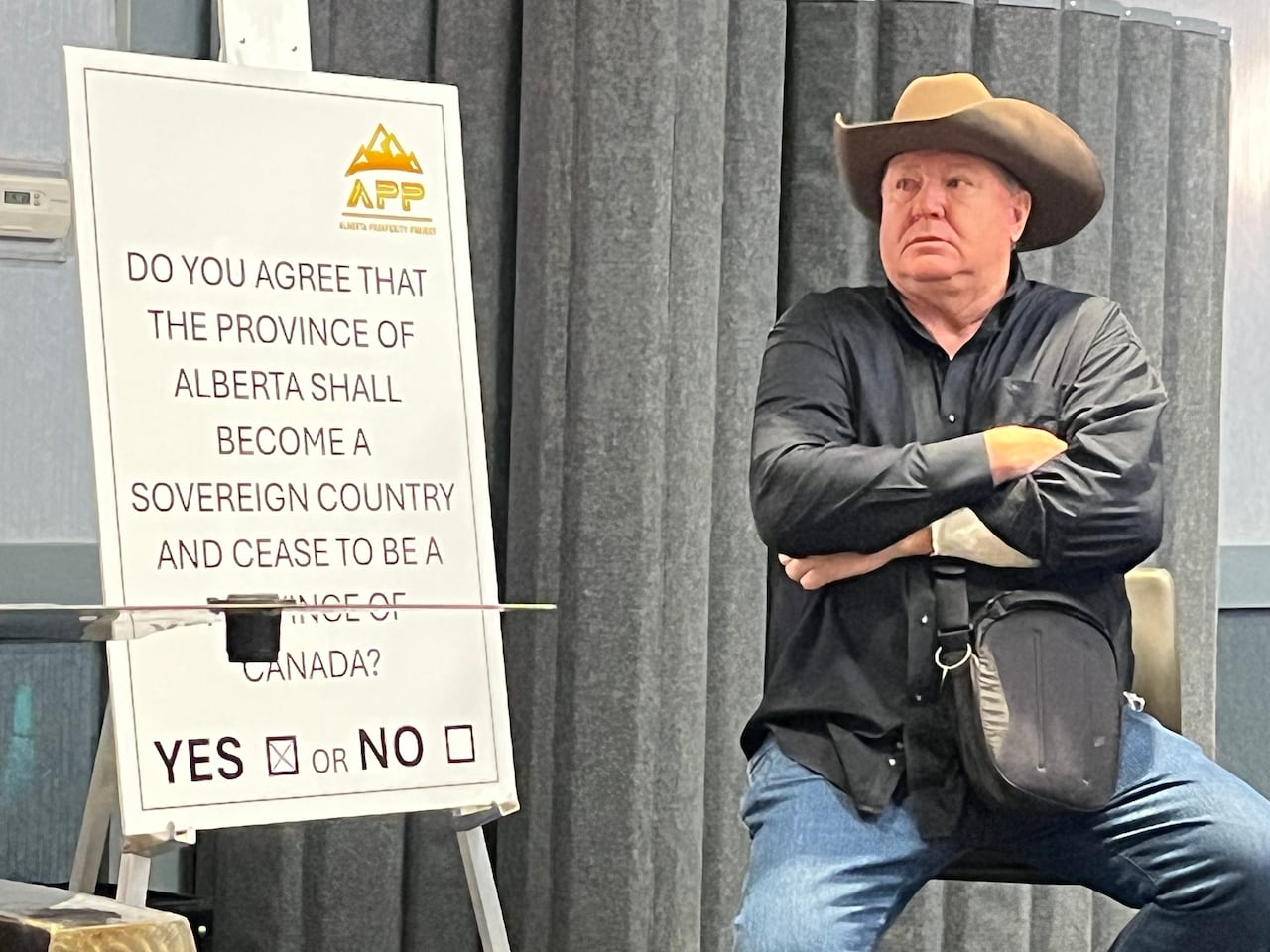 A man in a cowboy hat sits next to a referendum question.